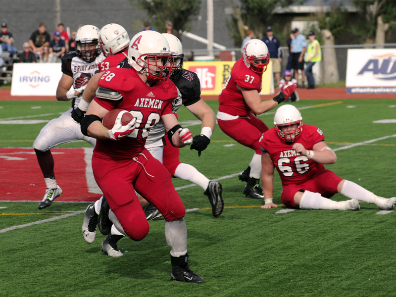 Acadia Axemen football players charge down the field.